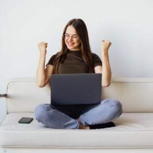Joyful woman on a sofa with a laptop using Office 365 modern work software